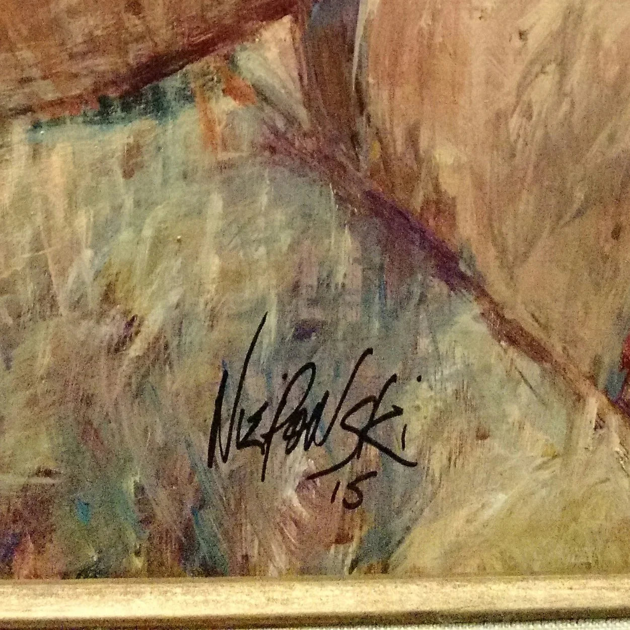Close-up of a painted canvas with an artist signature and abstract brushstrokes